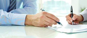 hands of two people with pens on paper